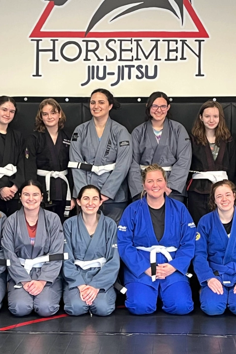A group of women smiling and posing together during a Brazilian Jiu Jitsu class at Horsemen BJJ in New Freedom, PA.