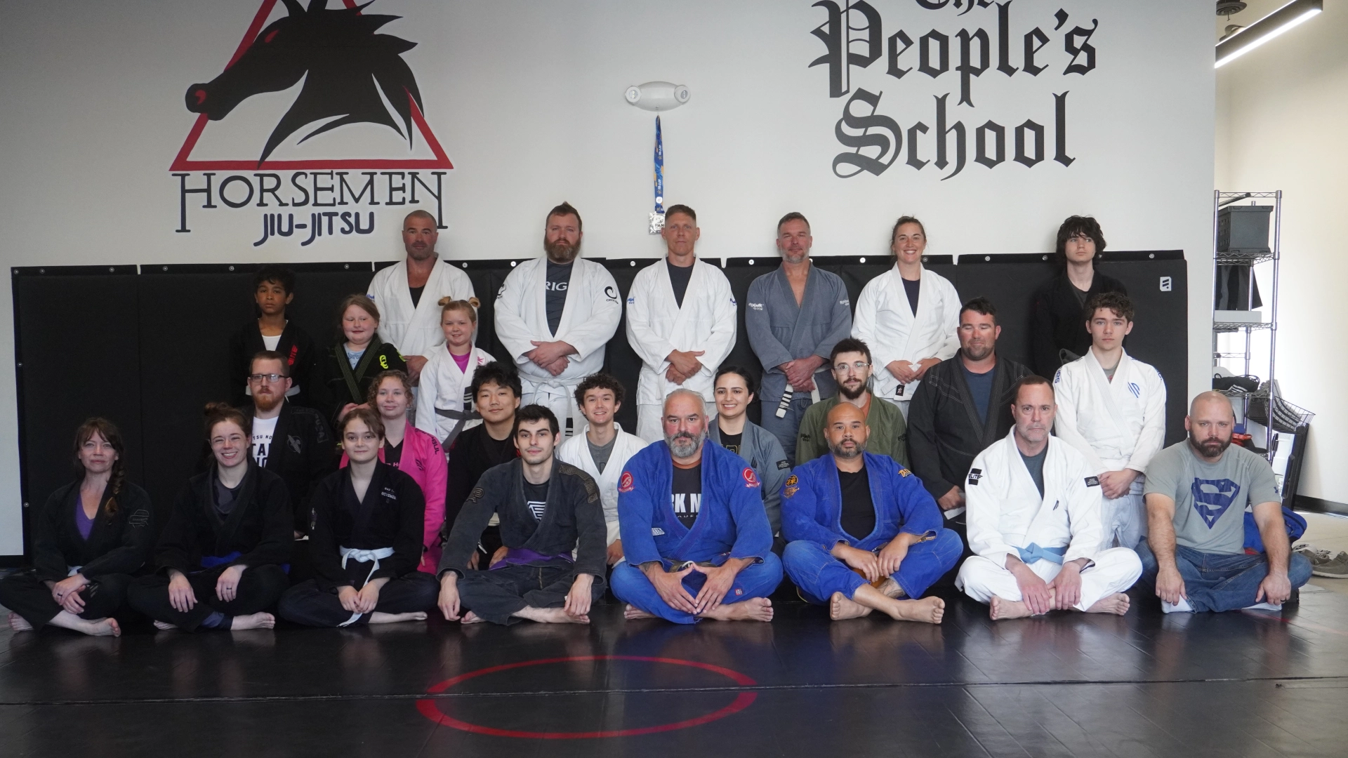 A group of people poses for a photo in a gym at Horsemen Brazilian Jiu Jitsu in New Freedom, PA.