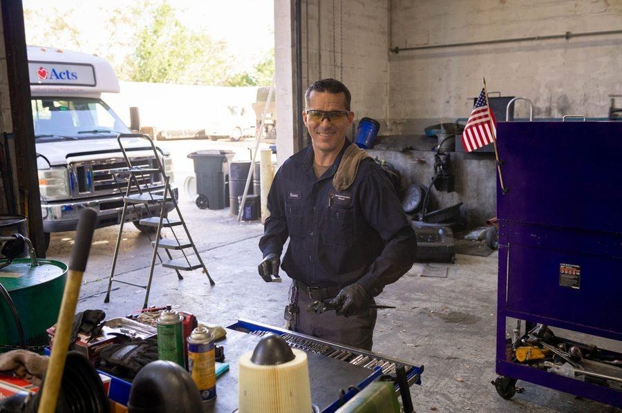 NH Repairs mechanic at workbench with tools and fluids working on heavy equipment component