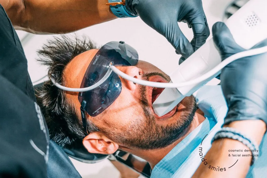 Male dental patient wearing protective glasses receiving treatment in the dental chair