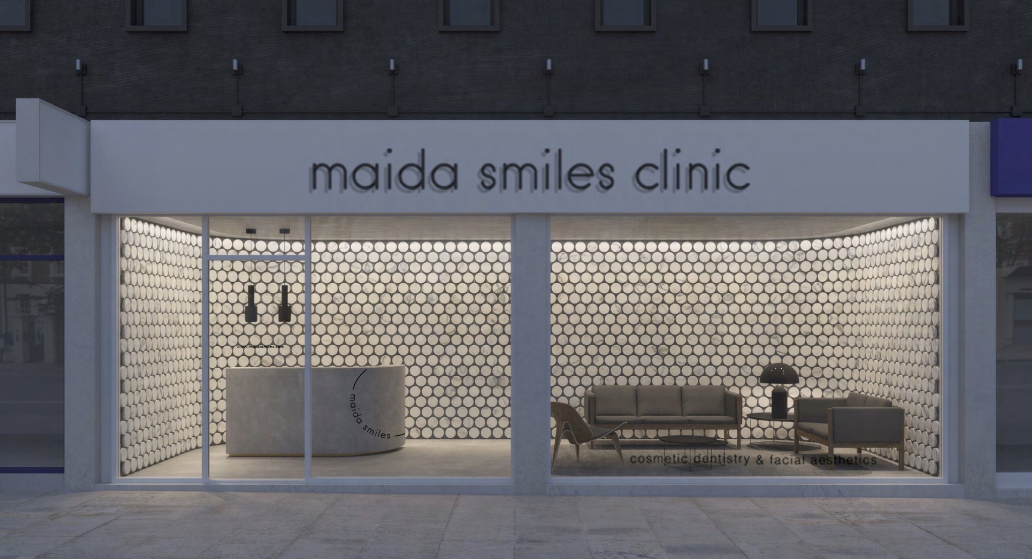 Maida Smiles Clinic exterior facade with illuminated signage and reception visible through the window at dusk
