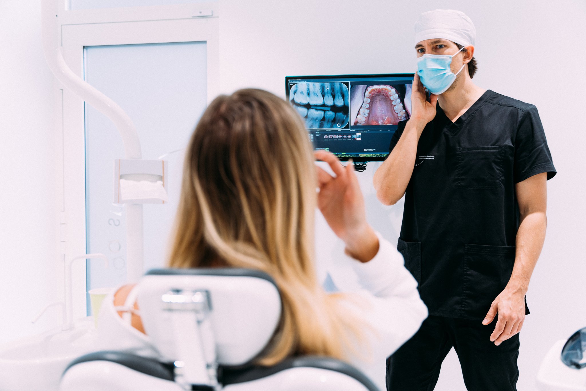 Dentist reviewing x-ray images on a monitor with a patient in the treatment chair