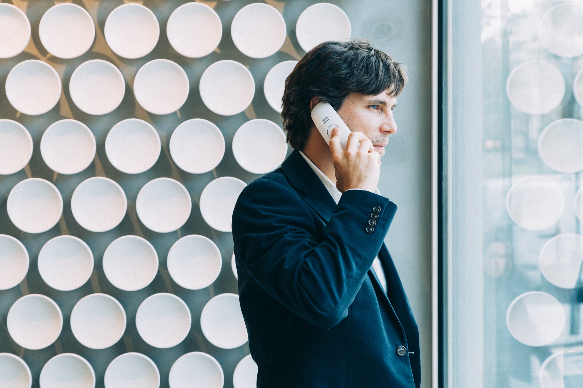 Man in a suit on the phone near a modern circular tiled wall in the clinic.
