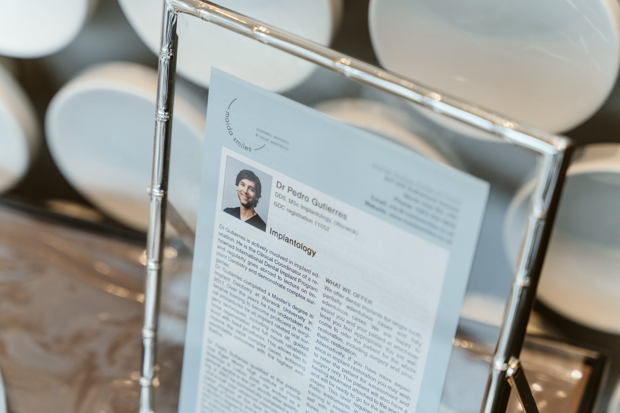 Close-up of a framed dental bio card focused on implant treatment expertise