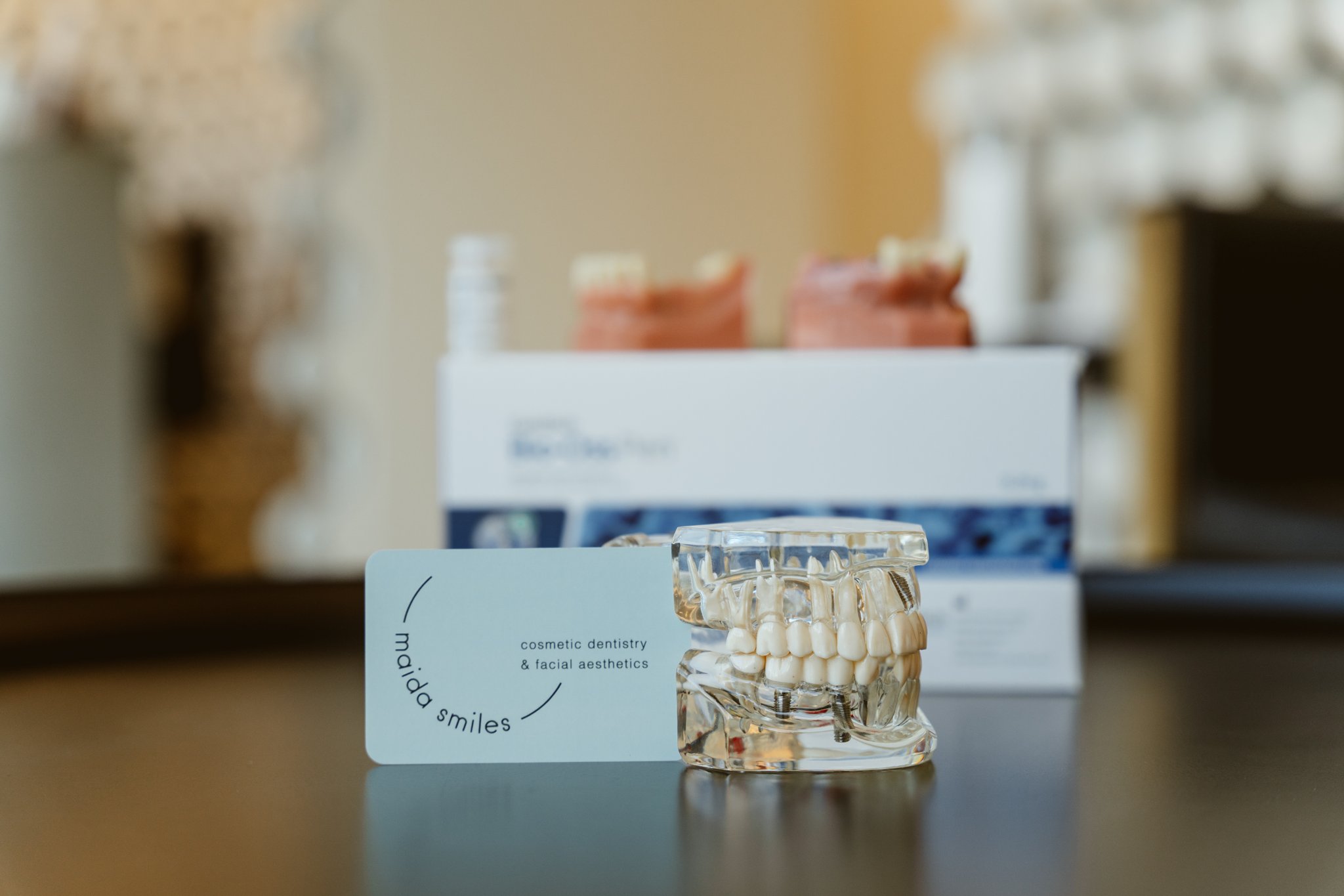 Close-up of clear dental implant model with visible screws and full arch of teeth
