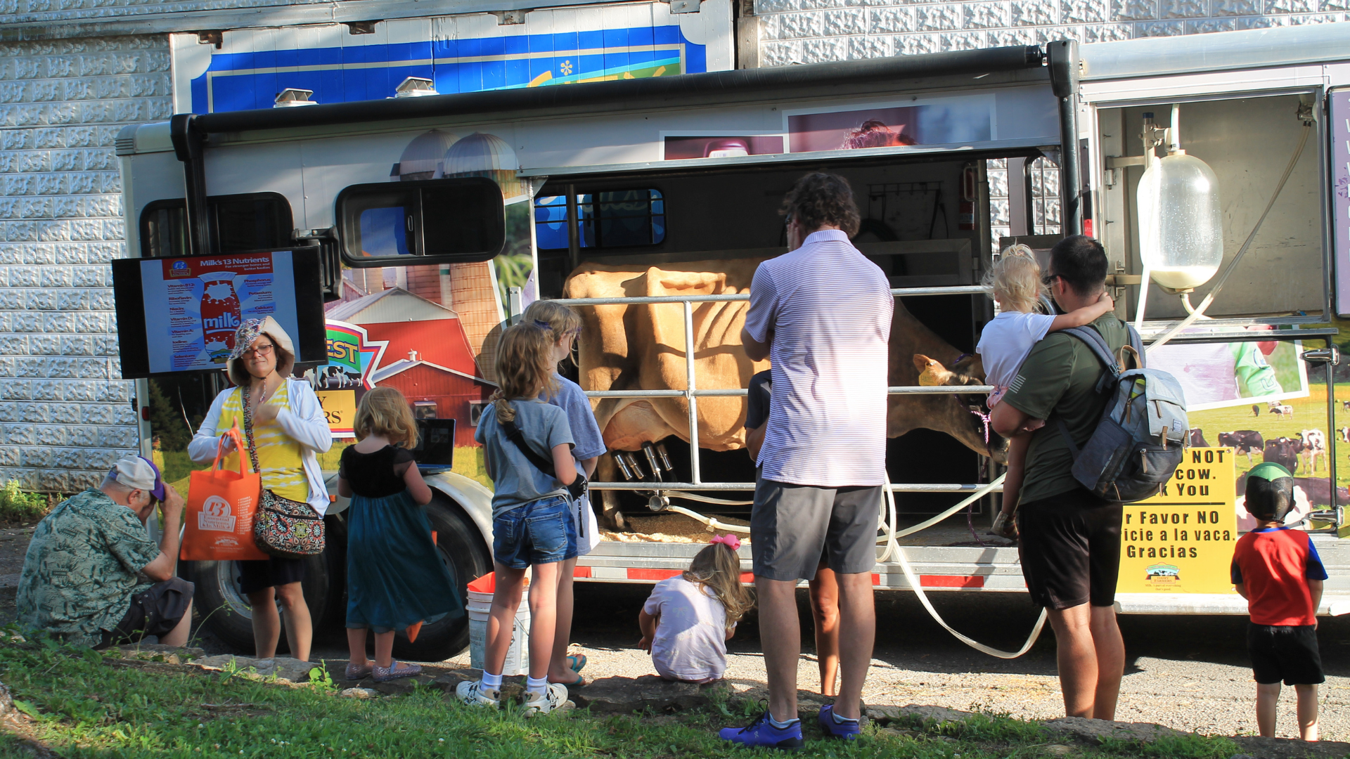 Man wearing a black cap and glasses sculpting a rock under a blue umbrella in an outdoor setting.