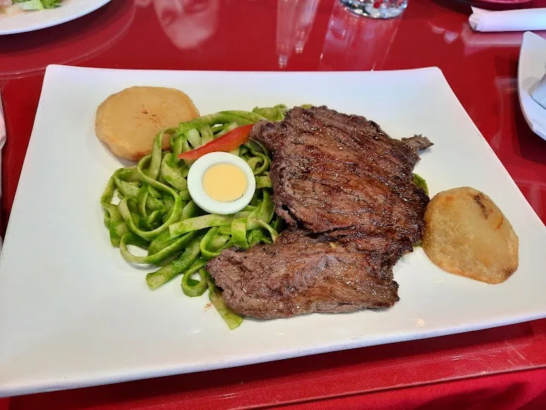 A juicy steak on a plate, accompanied by colorful vegetables and golden-brown potatoes.