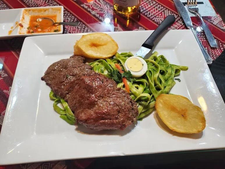 A plate of steak and noodles presented on a clean white dish.