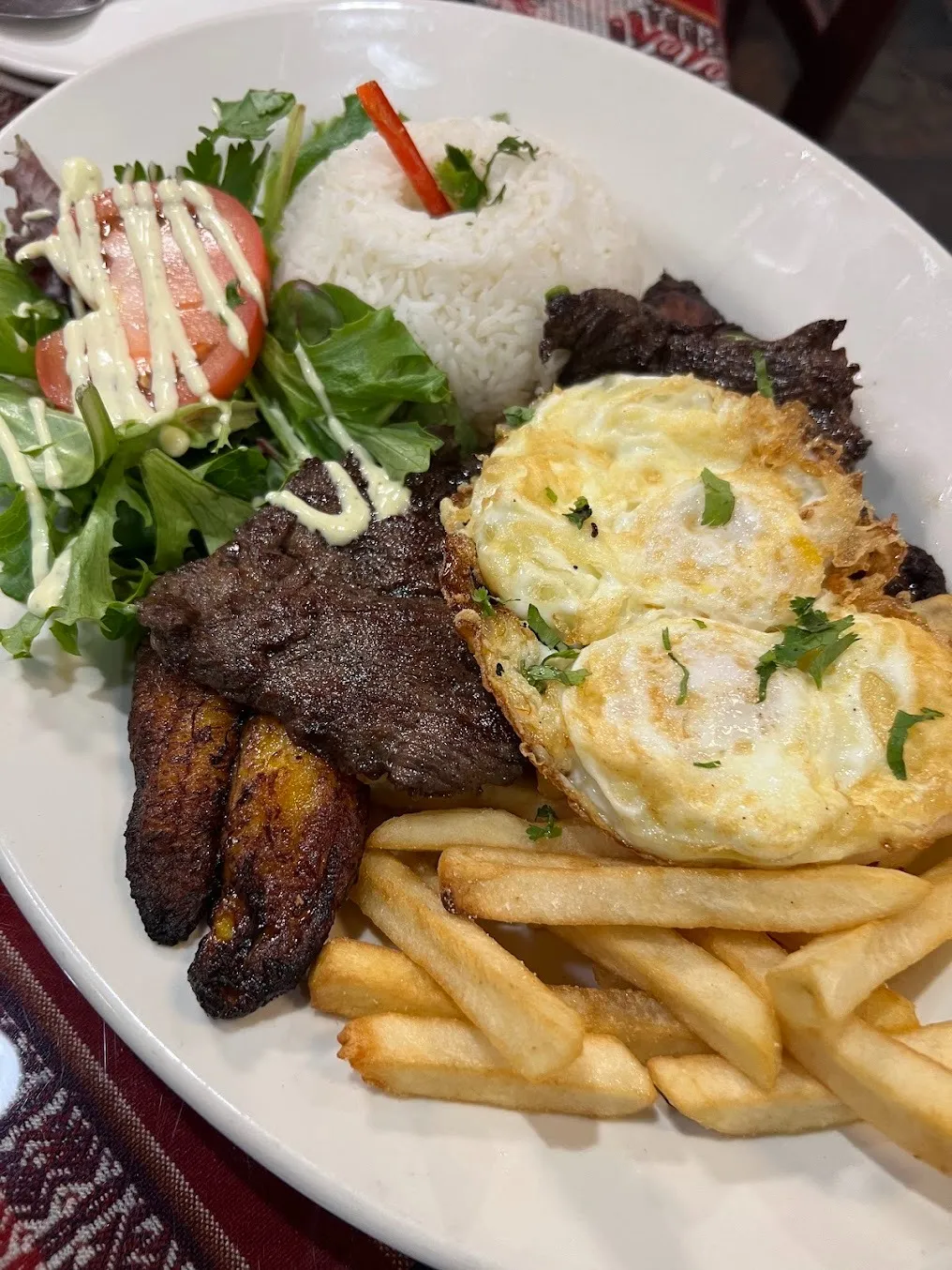 A plate featuring golden French fries, scrambled eggs, and a portion of cooked meat.