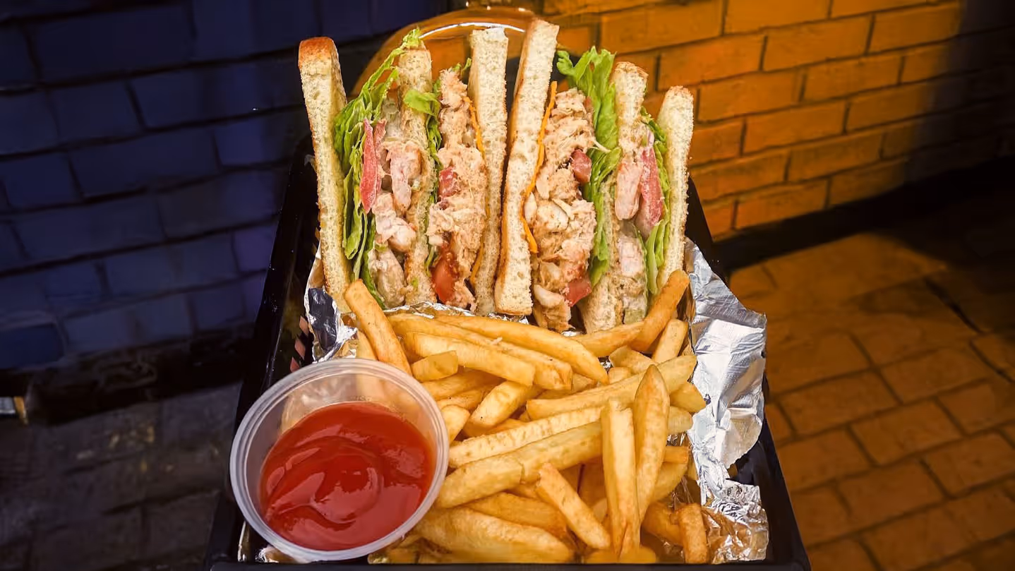 A club sandwich with fries and a cup of ketchup.