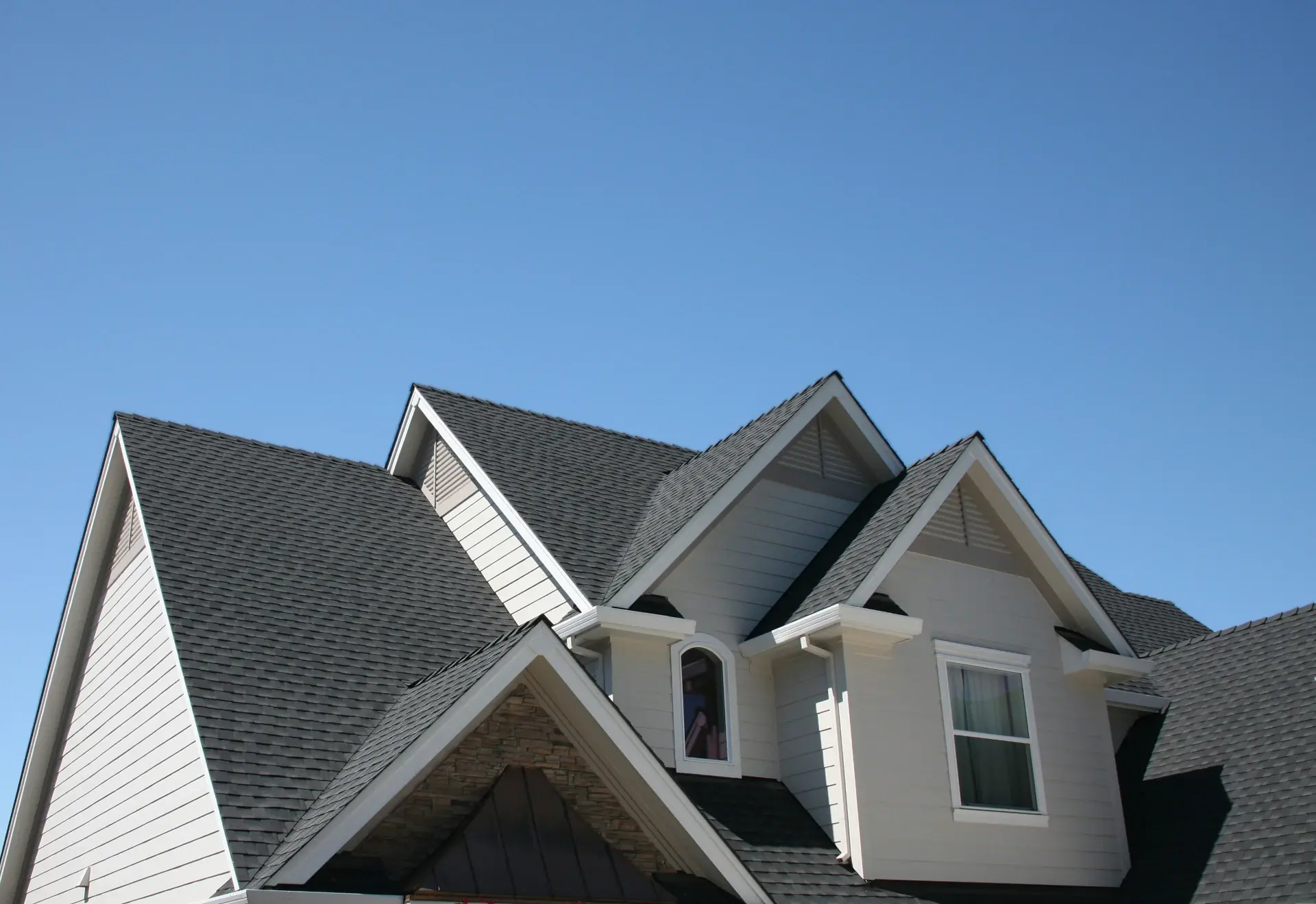 residential home with shingles in front of a blue sky