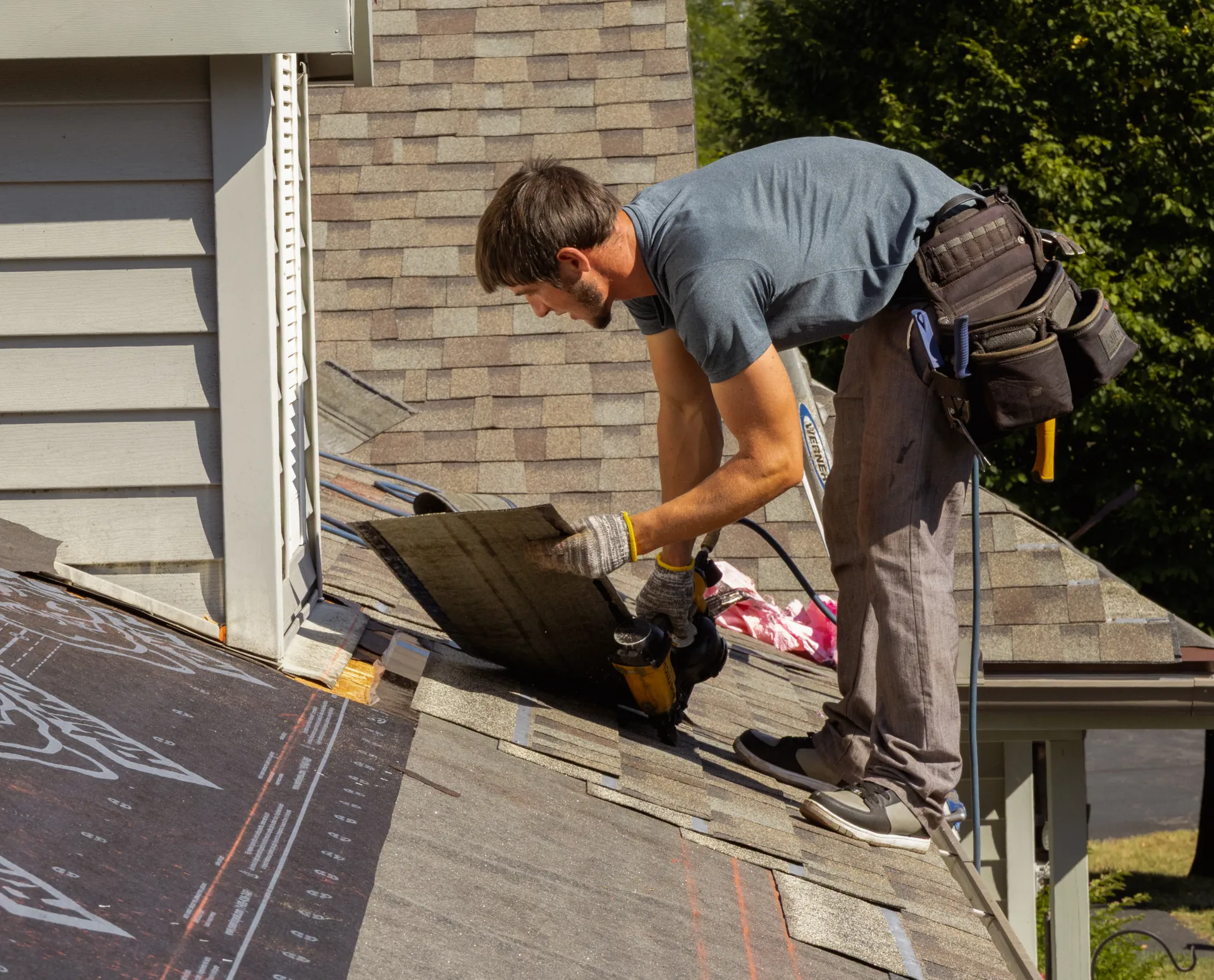 man working on replacing a shingle roof