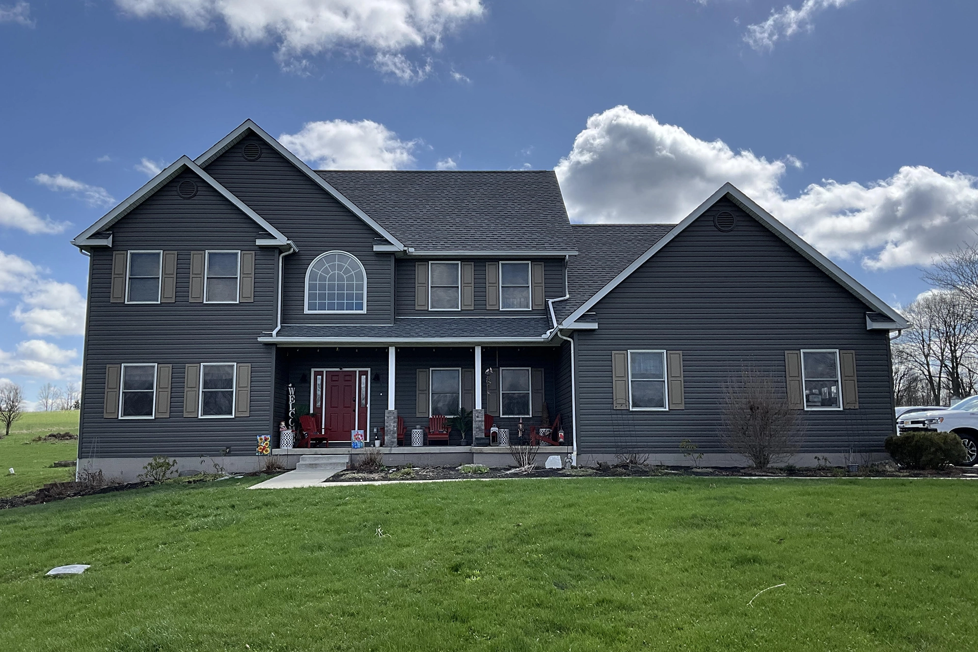 finished home with blue grey siding, a red door, attached garage, and big yard