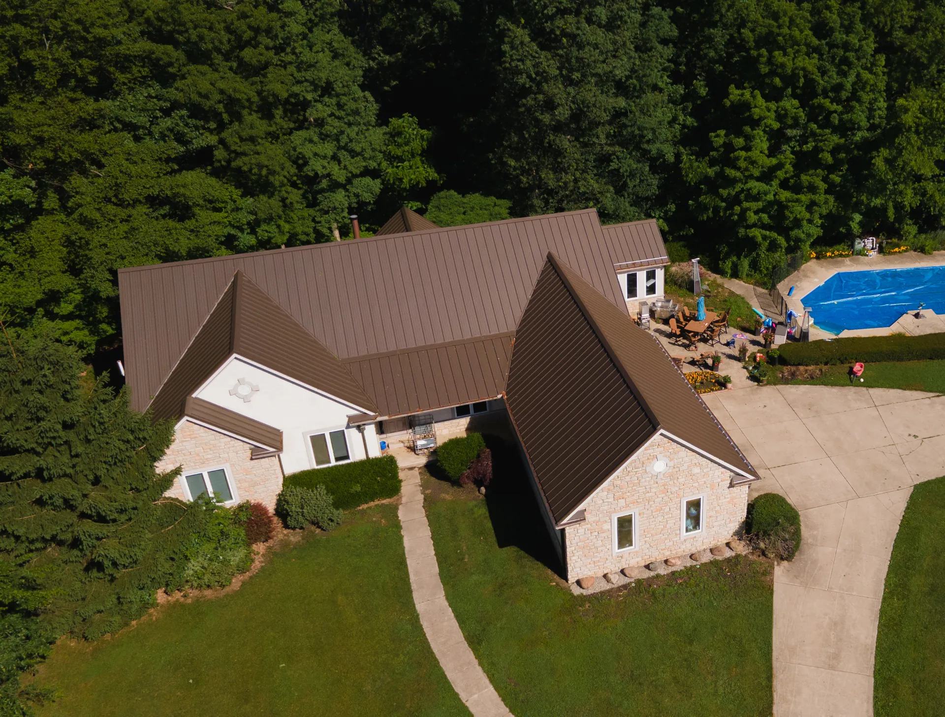 Brown metal roof on a large Ohio home surrounded by trees and landscaping.