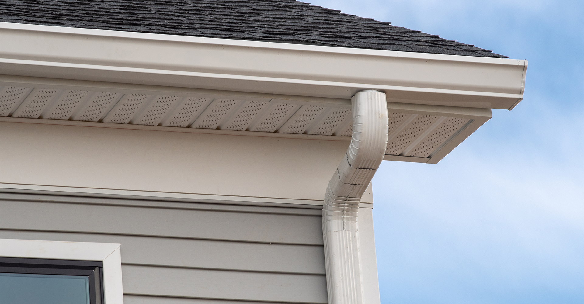 White downspout connected to a gutter system directing water away from a home's foundation