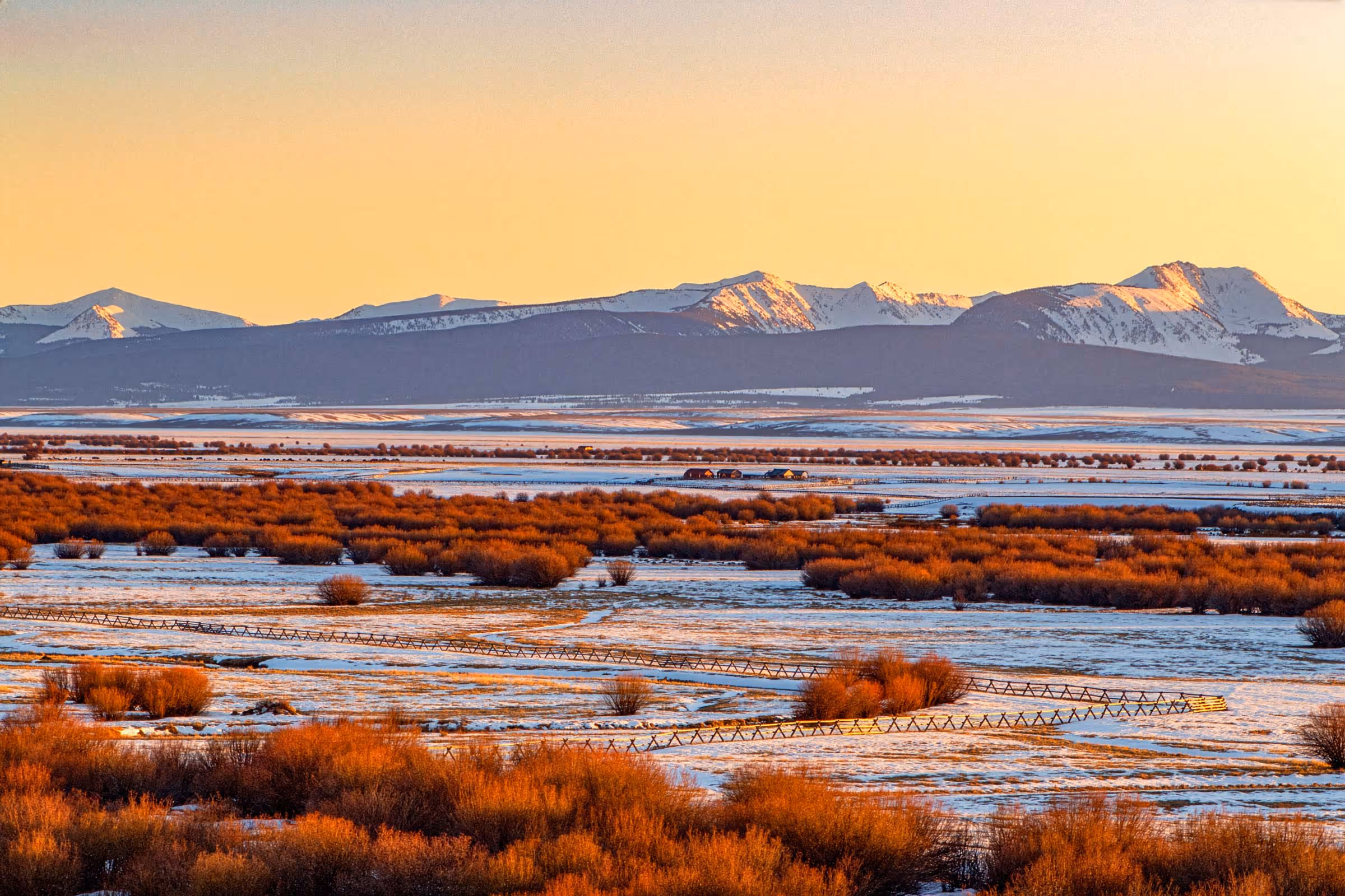 A winter valley and mountain range in the distance.