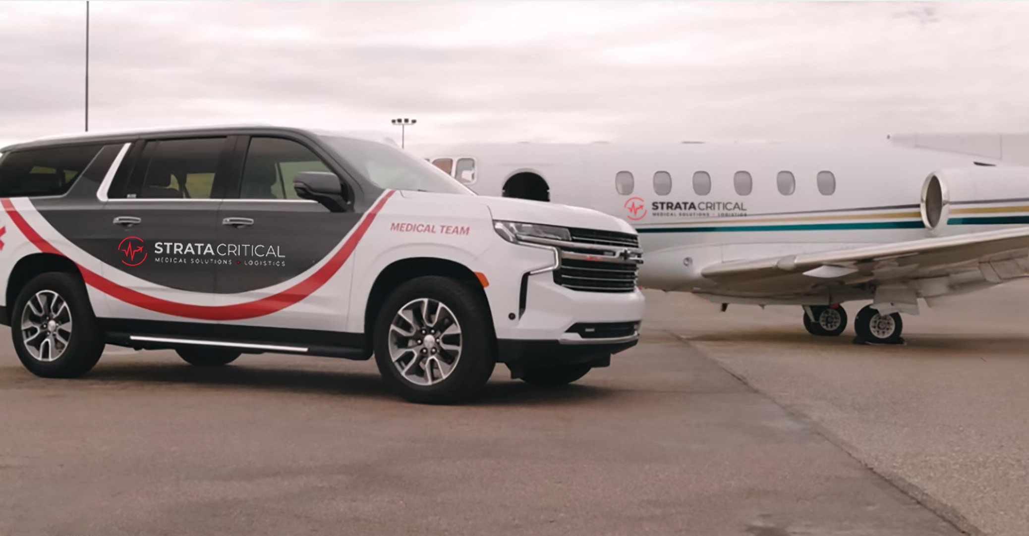 A strata critical branded SUV on the tarmac next to a Strata Critical branded jet. 