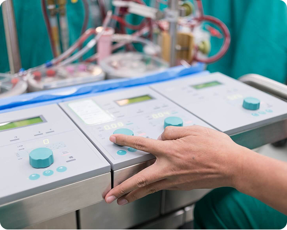 A hand adjusting controls on medical machinery with digital displays and knobs in a clinical setting.