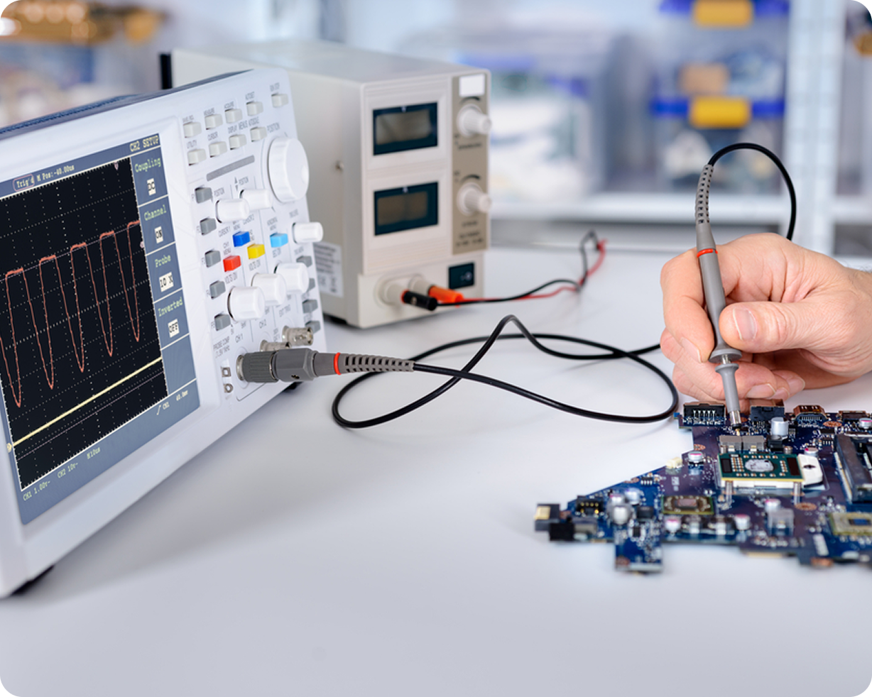 Hand testing electronics circuit board with oscilloscope showing waveform on screen.