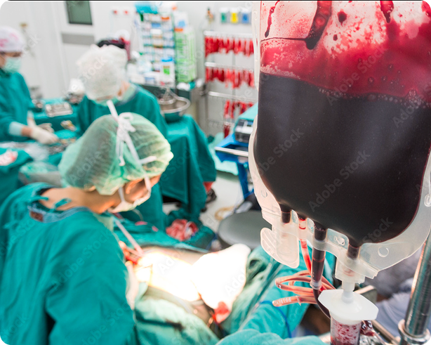 Healthcare professionals perform surgery in an operating room with a visible bag of blood transfusion.