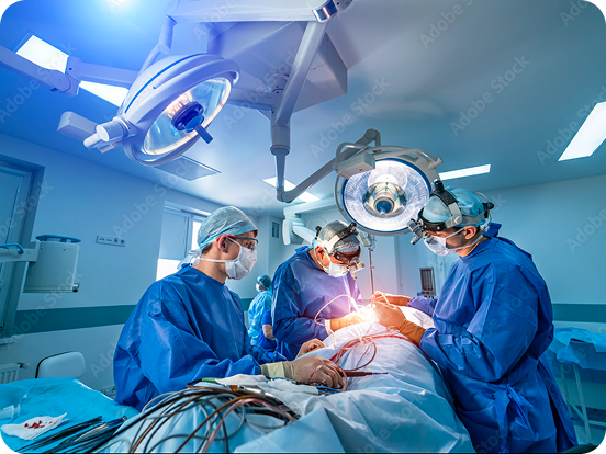 Surgeons in blue scrubs performing a surgical operation under bright lights in an operating room.
