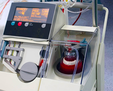 Blood donation machine with digital screen and blood bag inside clear compartment.