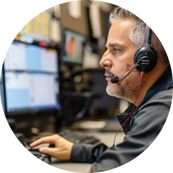 Man wearing headset and working on a computer in an office with multiple screens.