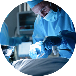 Surgeon in blue scrubs and mask performing an operation using surgical tools.