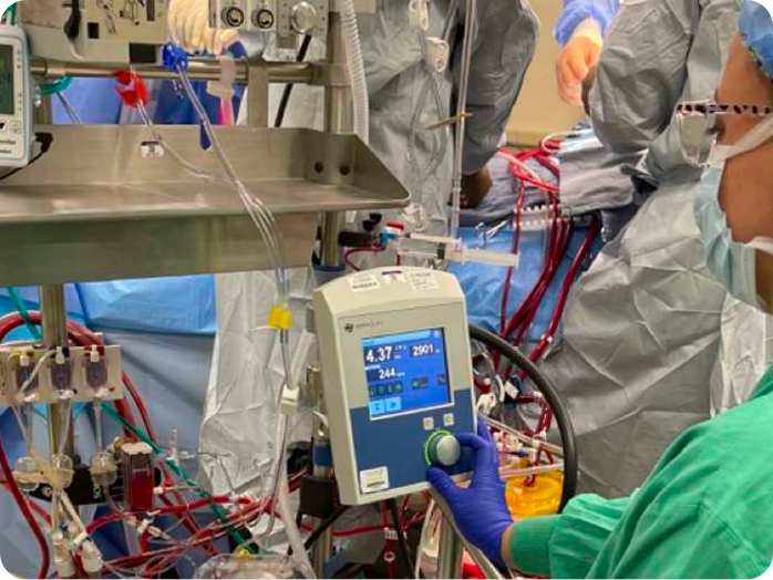 Three surgeons in blue scrubs performing surgery under bright operating room lights.
