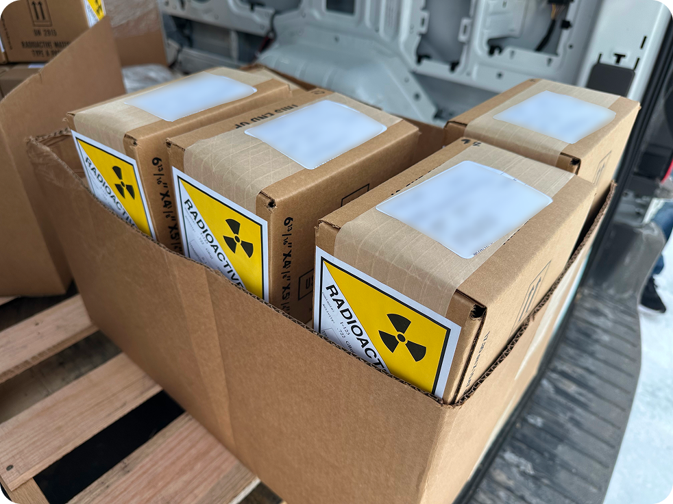 Cardboard box containing smaller boxes labeled with yellow radioactive hazard signs.