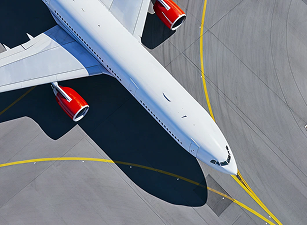 A large white airplane with red engines taxiing on gray tarmac with yellow guide lines.