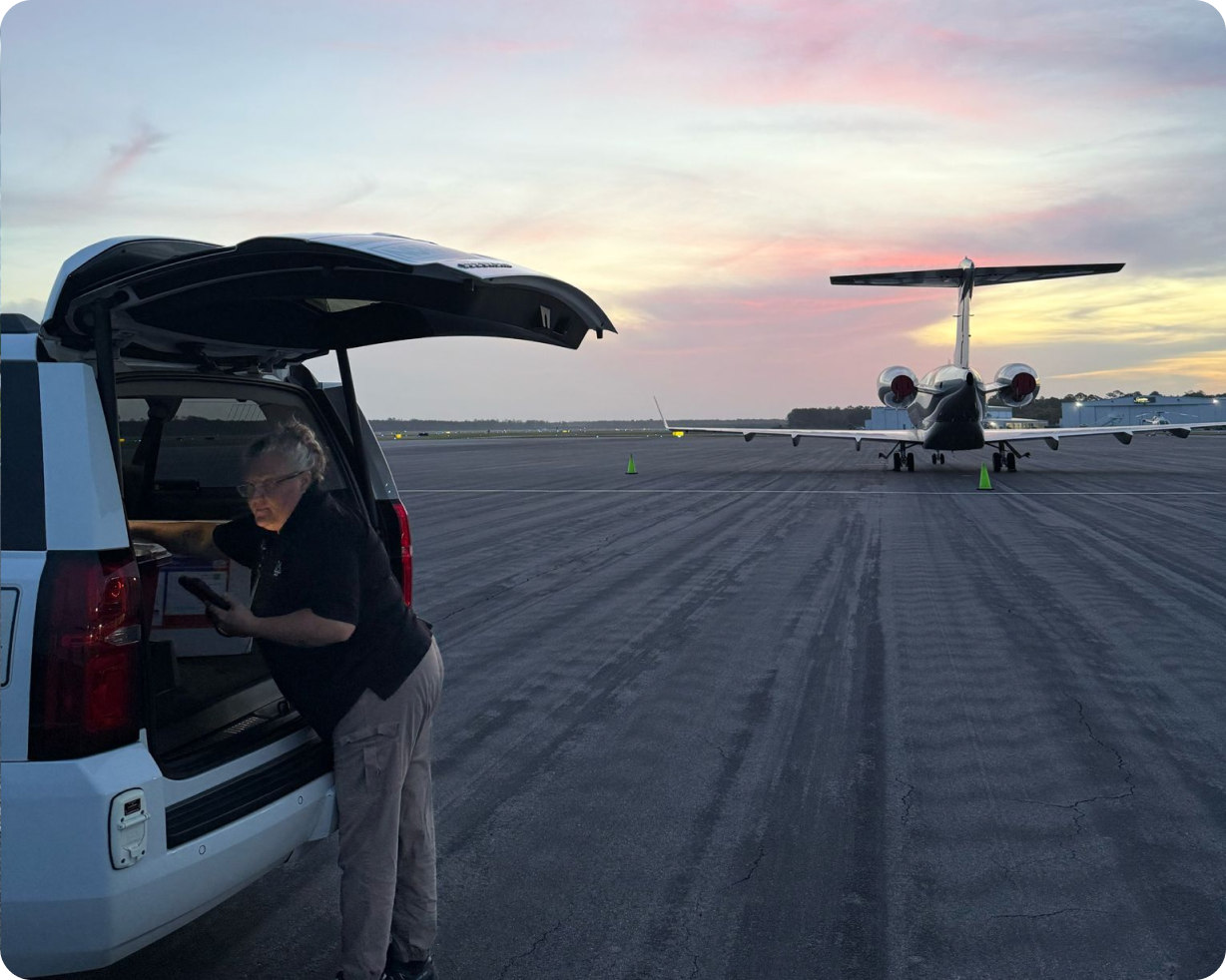 Medical team in scrubs assisting a patient onto a private jet ramp near a medical team SUV.