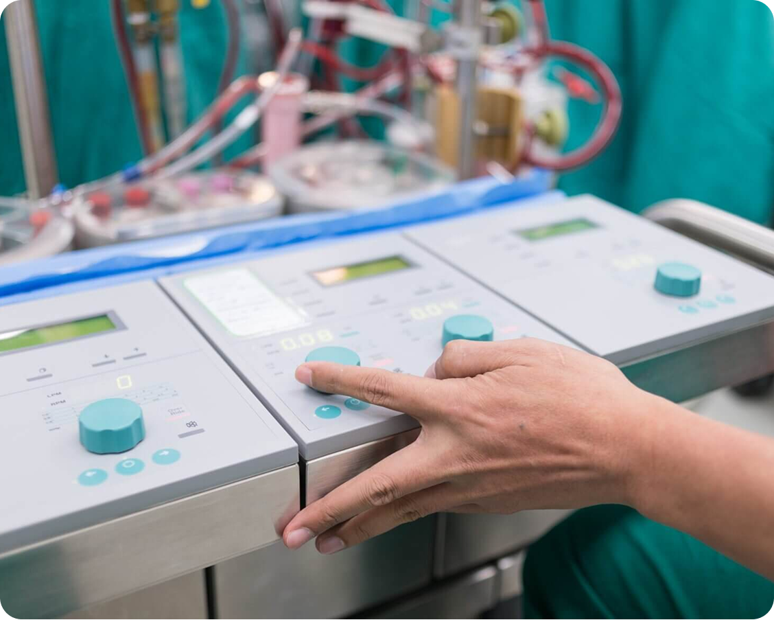 Hand adjusting control knobs on medical monitoring equipment in a clinical setting.