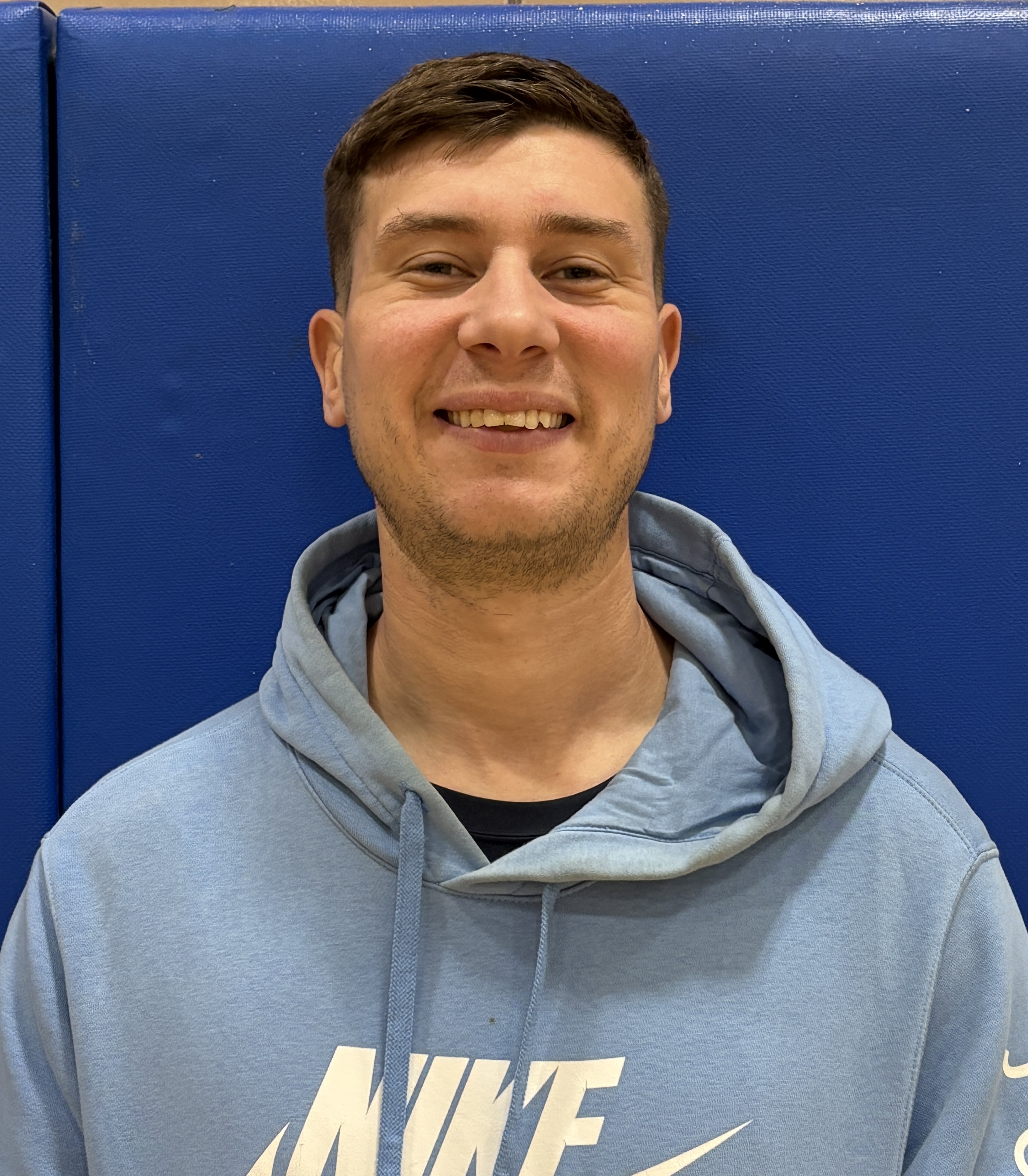 Staff member R. Salo smiling in school gymnasium