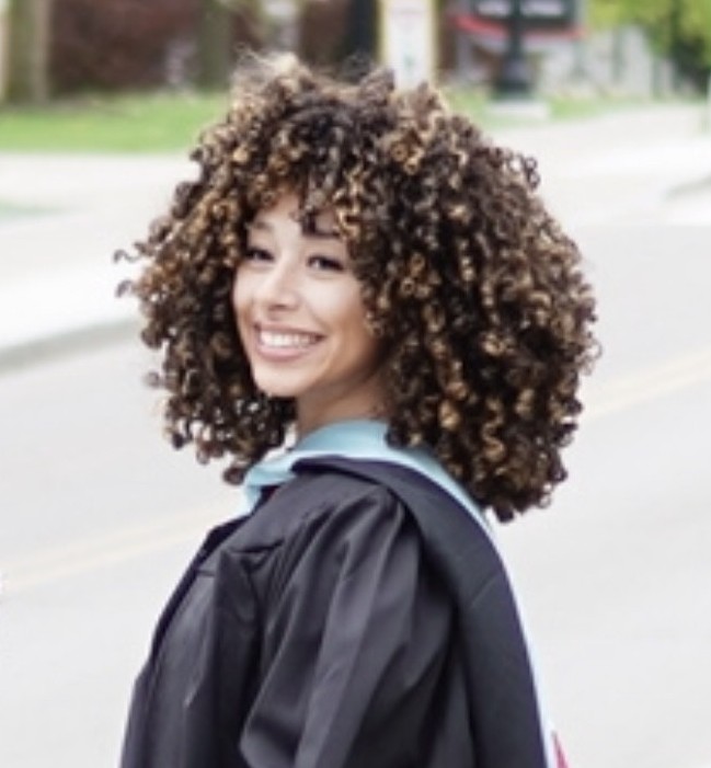 H. Santos smiling outdoors in graduation gown