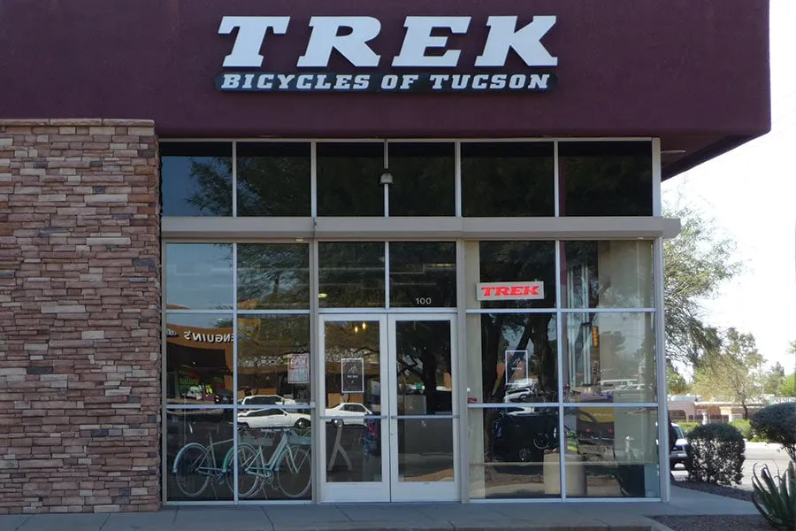Front entrance of Trek Bicycles of Tucson store with large glass windows and a bicycle displayed inside.