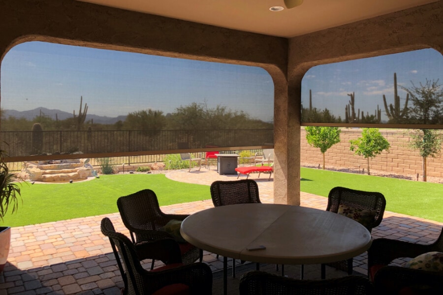 Patio with solar screens, chairs, and desert landscape.