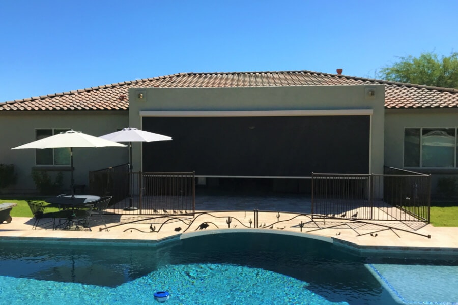 Poolside patio with large black outdoor screen, Tucson home.
