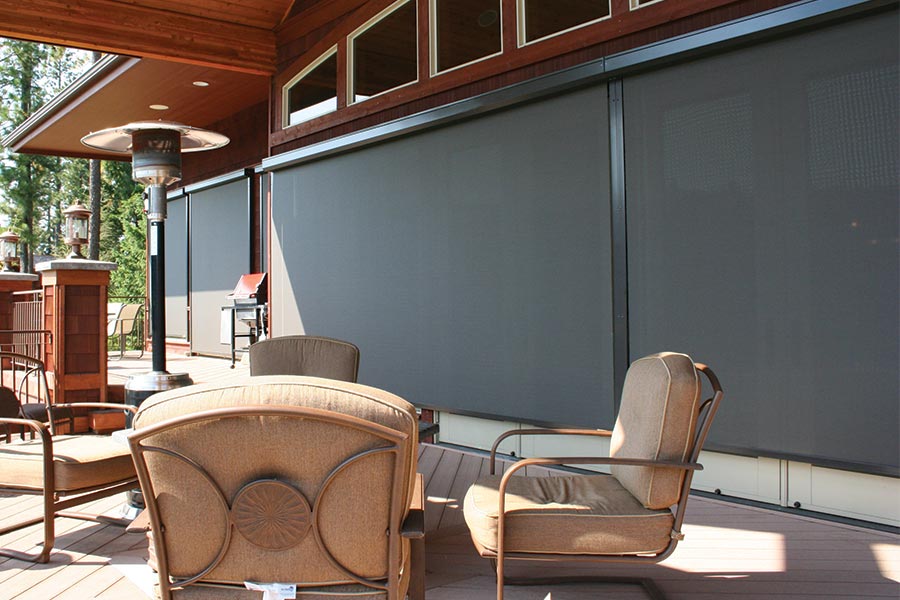 Outdoor patio with rolling solar screens in a residential setting.