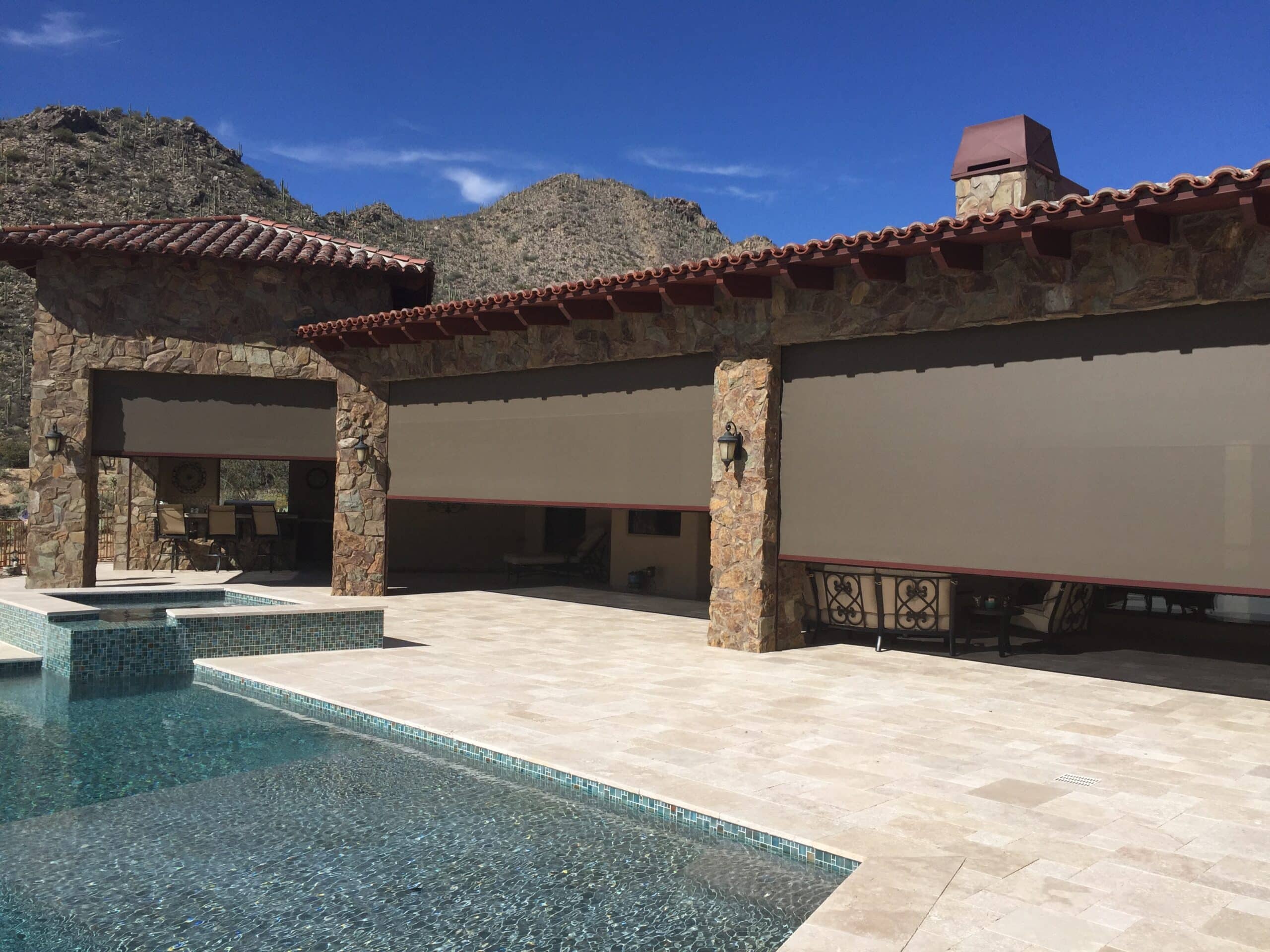 Outdoor solar screens on a stone house by a pool in Tucson.