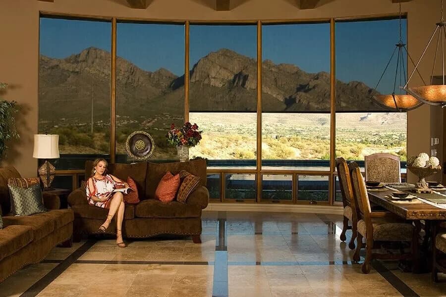 Woman reading on a sofa with large windows showing Tucson mountains.