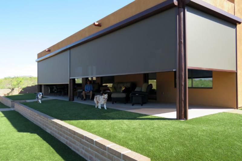 Patio with solar screens in Tucson, AZ with dogs and person under shade.