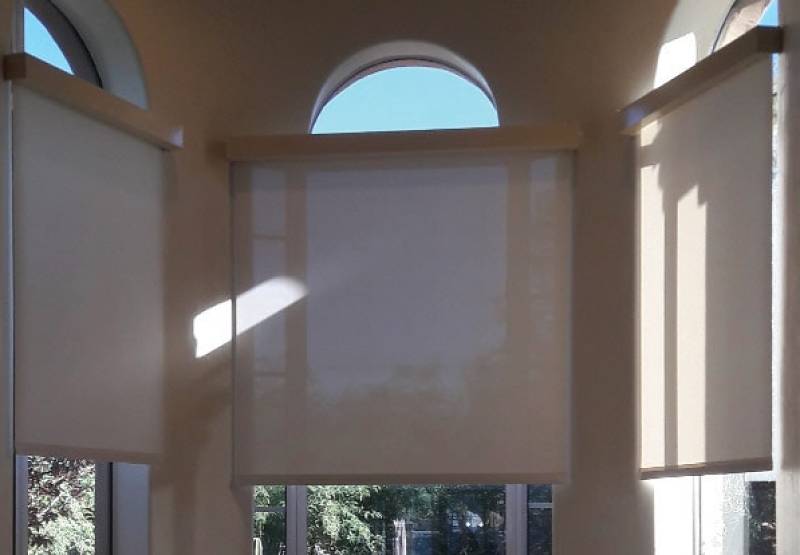 Indoor solar screens blocking sunlight through arched windows.