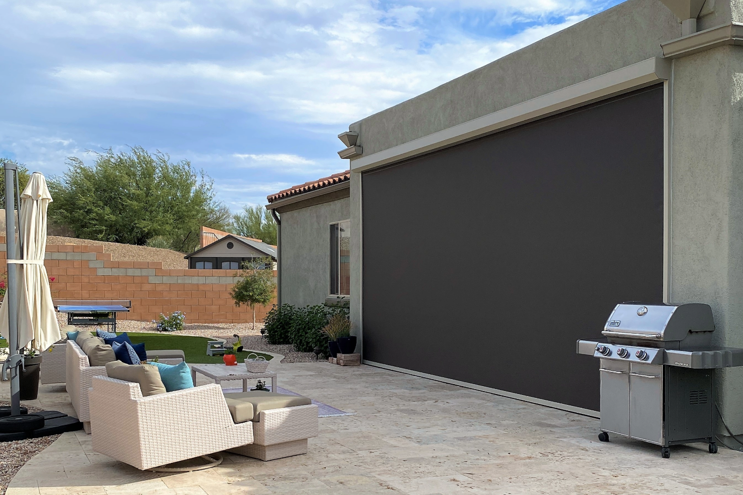 Patio with outdoor furniture, BBQ grill, and large rolling screen.