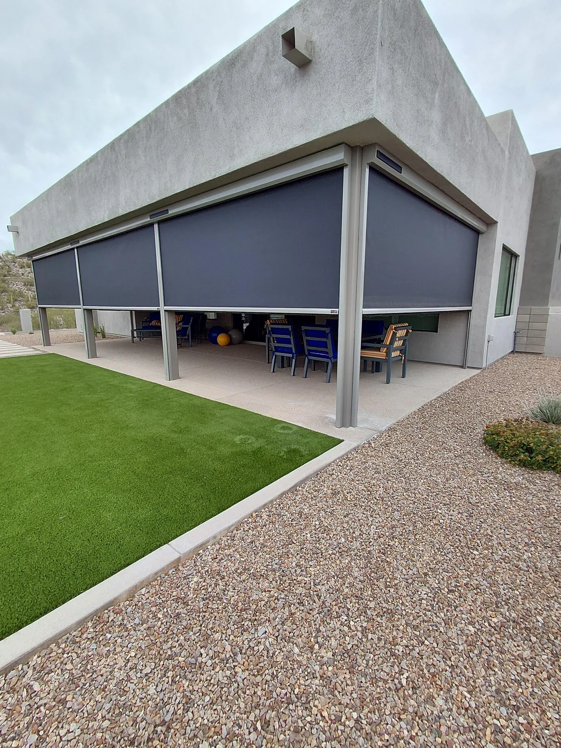Charcoal solar screens on modern home pergola with artificial turf lawn and outdoor seating