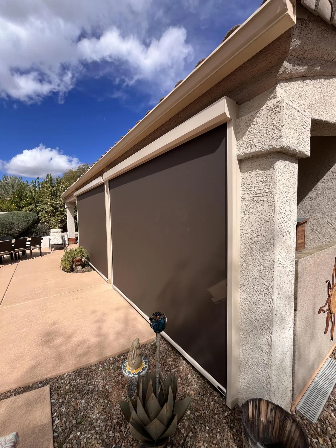 Solar screens on stucco patio with desert cactus garden, agave plants and decorative art