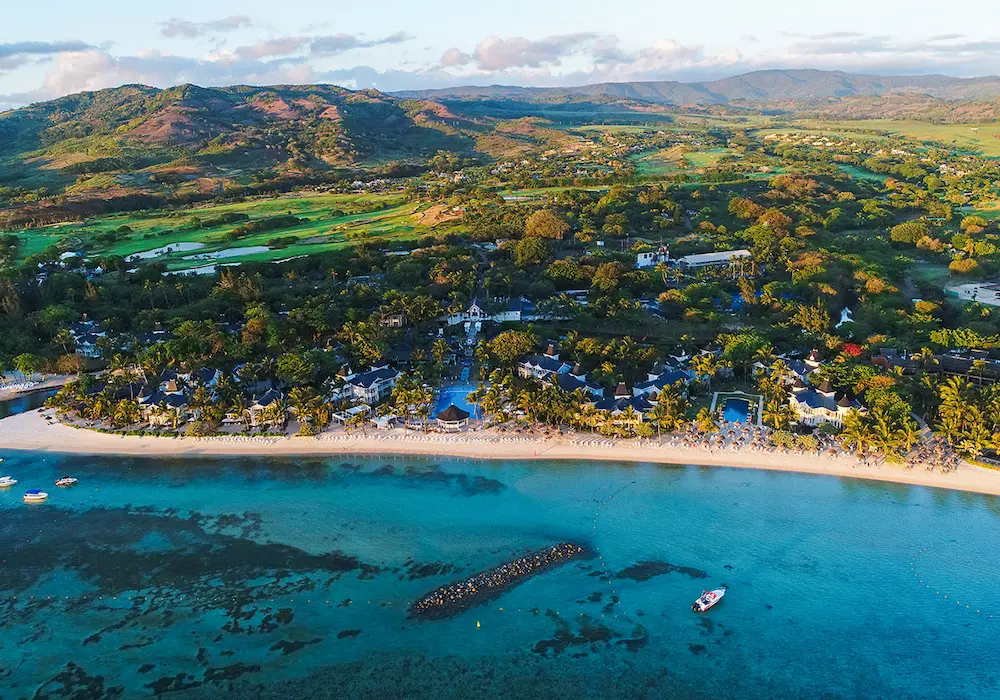 Aerial view of a luxury coastal resort in Mauritius with clear blue waters, lush greenery, and a golf course—Island Lilly’s tropical escape blending nature, wellness, and refined hospitality
