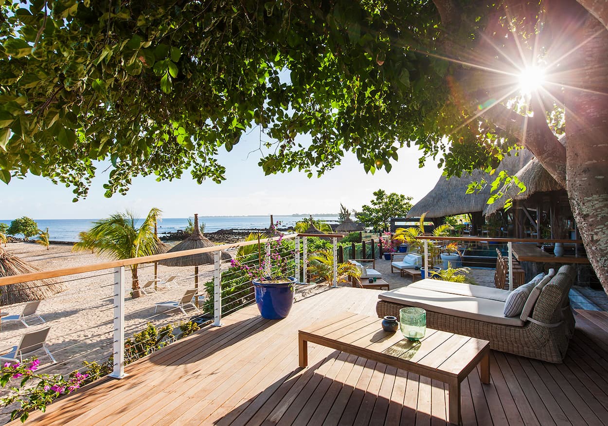 Beachfront deck with cushioned lounge chair, flowering railings, and ocean view in Mauritius—Island Lilly’s tranquil space for private relaxation and coastal serenity