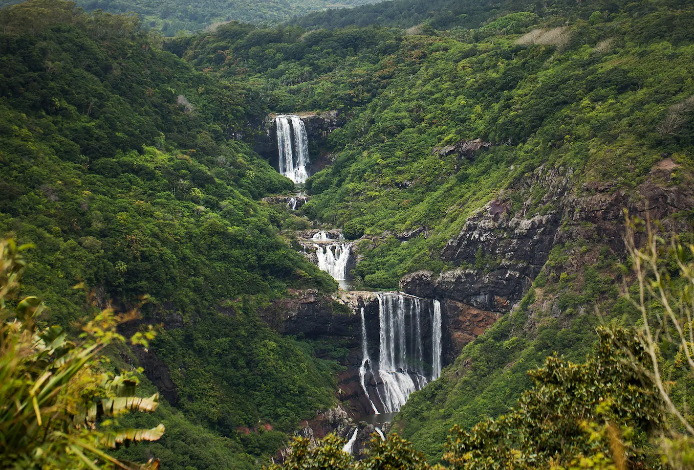 Verdant waterfall landscape in Mauritius with cascading cliffs and tropical foliage—Island Lilly’s immersive nature retreats rooted in serenity and renewal