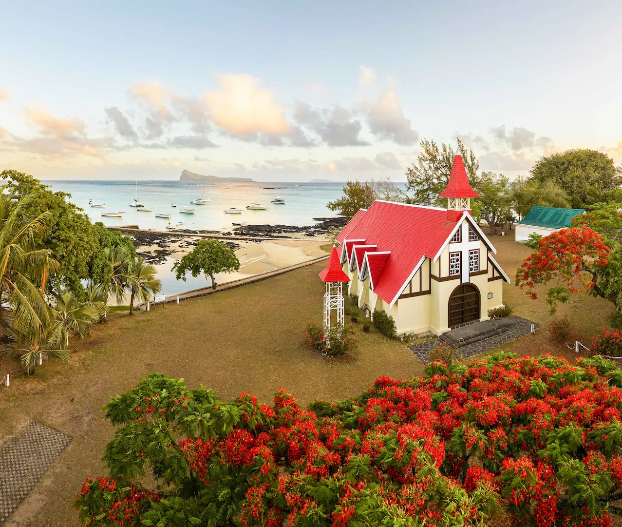 Aerial view of Macondé coastal road winding around a lush cliffside in Mauritius, with ocean and bay below—Island Lilly’s scenic route to discovery and connection